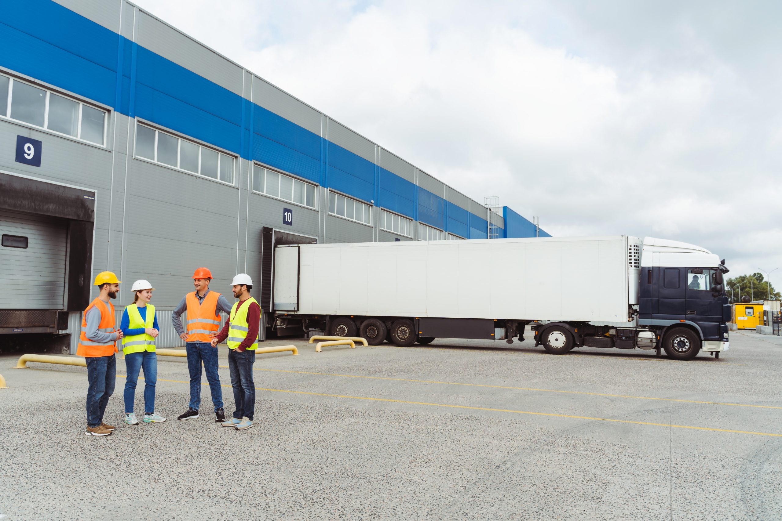 workers in hardhats standing in front of semi trucks